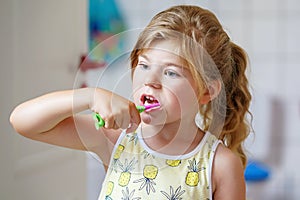 Cute little girl with a toothbrush and toothpaste in her hands cleans her teeth and smiles. Happy preschool child