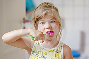 Cute little girl with a toothbrush and toothpaste in her hands cleans her teeth and smiles. Happy preschool child