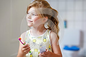 Cute little girl with a toothbrush and toothpaste in her hands cleans her teeth and smiles. Happy preschool child