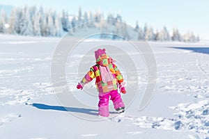 Cute little girl treads through the snow on the mountain