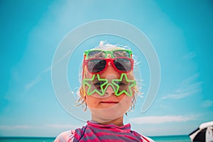 Cute little girl try on sunglasses on beach