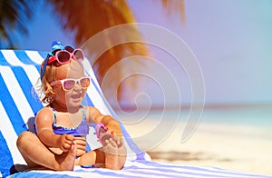 Cute little girl trying on sunglasses at the beach