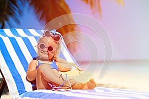 Cute little girl trying on sunglasses at the beach