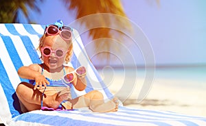 Cute little girl trying on sunglasses at beach