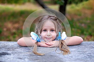 Cute little girl with two pigtails on her head fold hands near face. Concept of happy childhood and summer leisure. Smiling child