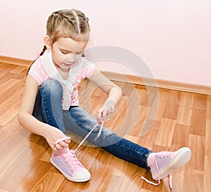 Cute little girl tying her shoes