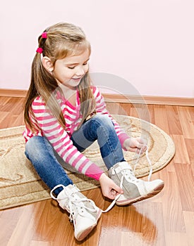 Cute little girl tying her white shoes