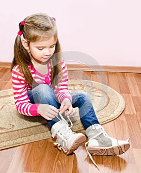 Cute little girl tying her white shoes