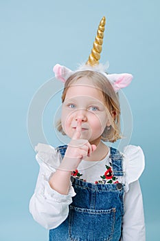 Cute little girl in unicorn head band over blue background