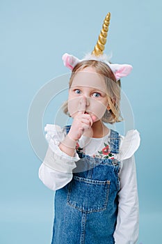 Cute little girl in unicorn head band over blue background