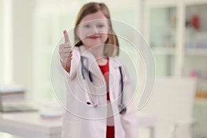 Cute little girl in uniform of medic shows thumb up gesture