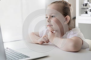Cute little girl using laptop at home. Education, online study, home studying Kids distance learning
