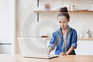 Cute little girl using laptop at home. Education, online studying, technology, distance learning, homework, schoolgirl children