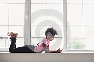 Cute little girl using smart phone at home. Student teenager texting on her mobile phone