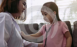 Cute little girl using stethoscope to listen to doctor heartbeat