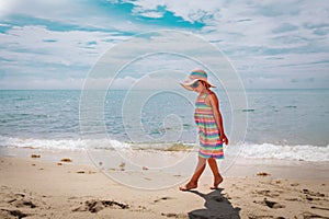 Cute little girl walk on tiptoes on summer beach vacation