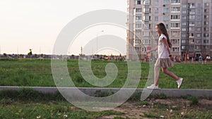 Cute little girl walking on concrete log on city lawn