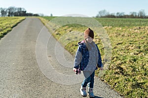 Cute little girl walking on a country road on a sunny day