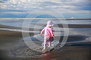 Cute Little girl walking on New Plymouth beach, NZ photo