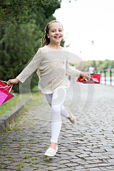 Cute little girl walking with the pink shopping bags