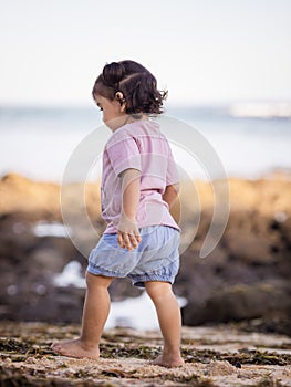 Cute little girl walking on sandy beach. Warm sunny day. Happy childhood. Summer vacation. Holiday at the sea. Baby girl wearing