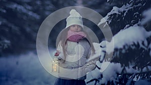 A cute little girl walks through a snowy wild forest in the evening with a lantern in winter in frosty weather.