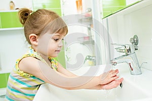 Cute little girl washing her hands in bathroom