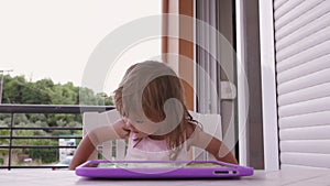 Cute little girl watching tablet on the terrace