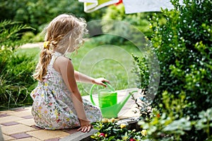 Cute little girl watering plants in the garden.