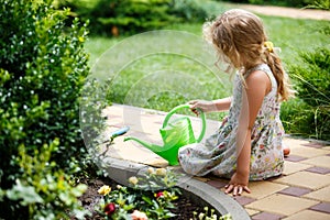 Cute little girl watering plants in the garden.