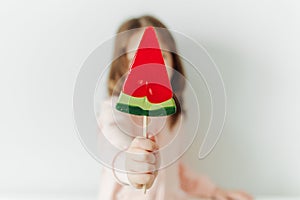 Cute little girl with watermelon lollipop. White background. Vacation and summer mood concept