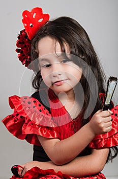 Cute little girl wearing beautiful red and black dress with matching head band, posing for camera using chinese hand fan