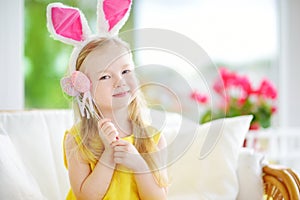 Cute little girl wearing bunny ears playing egg hunt on Easter