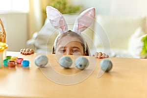 Cute little girl wearing bunny ears playing egg hunt on Easter