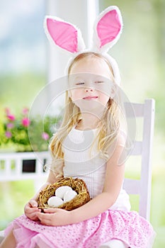 Cute little girl wearing bunny ears playing egg hunt on Easter