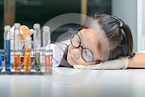Cute little girl wearing glasses and lab coat making experiment photo