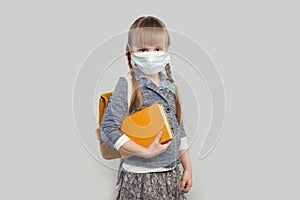 Cute little girl wearing medical protective face mask on white background