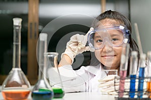 Cute little girl wearing safty goggle and lab coat making experiment