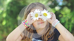 Cute little girl with wet hair, playing with   Shasta daisy flowers, making faces, having fun; positive emotions, slow motion
