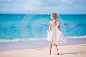 Cute little girl in white dress at beach during caribbean vacation