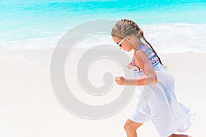 Cute little girl in white dress at beach during caribbean vacation