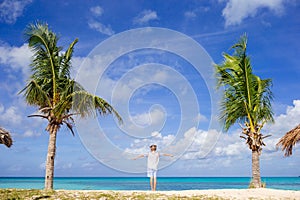 Cute little girl in white dress and hat at beach during caribbean vacation.