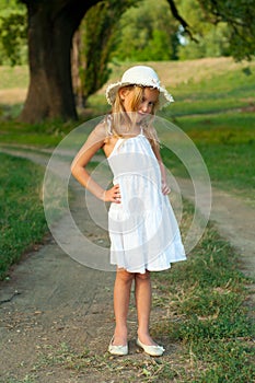 Cute little girl in white dress and hat standing