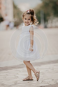 Cute little girl in white dress, posing and smiling