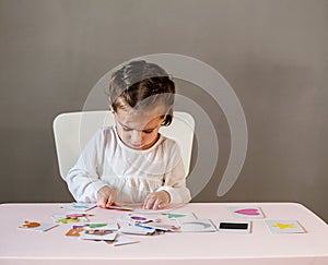 Cute little girl in white shirt playing puzzle.