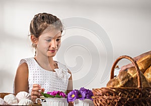 Cute little girl in a white sundress drinks tea