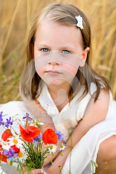 Cute little girl with wild flowers red poppy bouquet