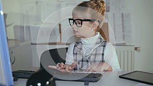 Cute little girl willingly works with pc in office. 4K