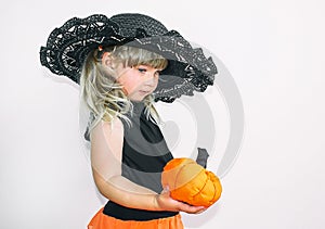 Cute little girl in witch costume with pumpkins. Halloween. On a white background.