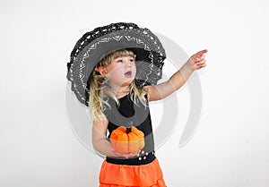 Cute little girl in witch costume with pumpkins. Halloween. On a white background.